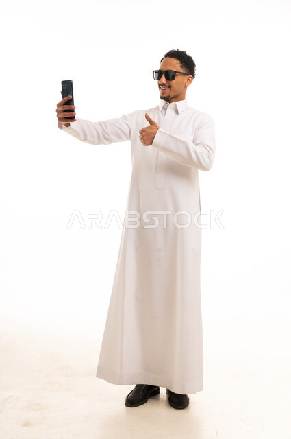 رجل سعودي بالثوب الأبيض يلتقط سيلفي مع علامة الإعجاب