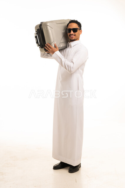 رجل سعودي بالثوب يحمل حقيبة سفر في الاستوديو