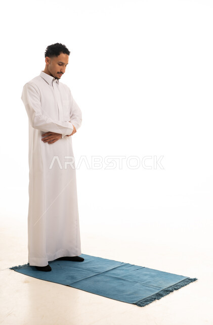 رجل سعودي بالثوب الأبيض يصلي على السجادة