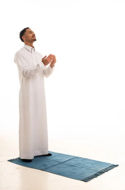 رجل سعودي يرتدي الثوب التقليدي يدعو الله على سجادة الصلاة