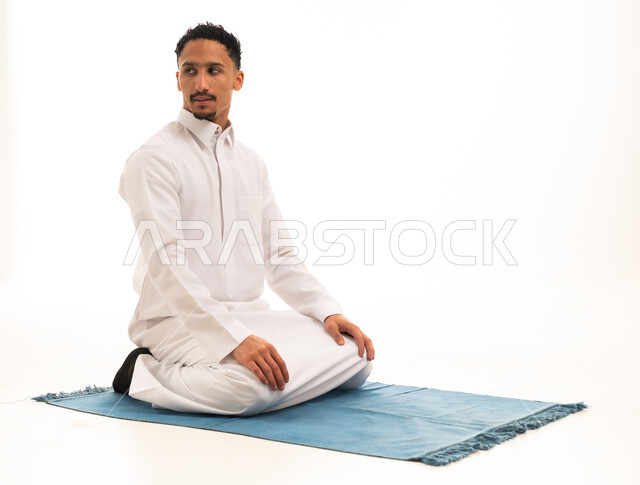رجل سعودي بالثوب الأبيض على سجادة صلاة