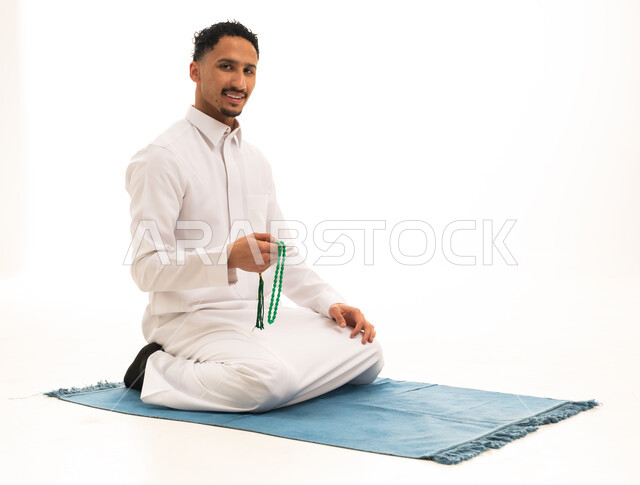 رجل سعودي بالثوب التقليدي يحمل مسبحة خضراء