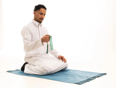 Saudi Man in White Thobe Praying on Rug
