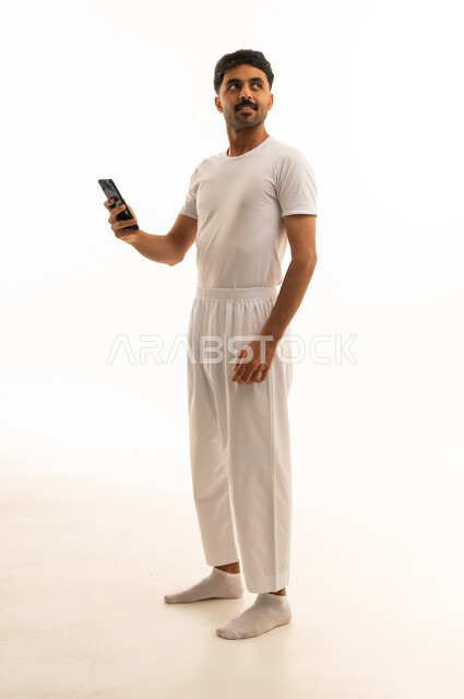 رجل سعودي بالملابس الداخلية البيضاء يمسك هاتف ذكي