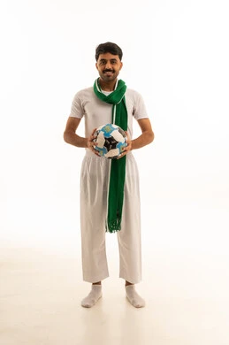 رجل سعودي يحمل كرة قدم مع وشاح أخضر