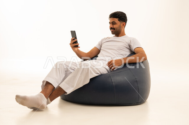 رجل سعودي يستخدم الهاتف الذكي على كرسي بين باج