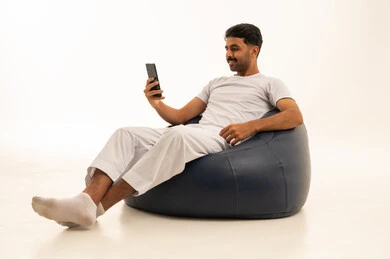 رجل سعودي يستخدم الهاتف الذكي على كرسي بين باج