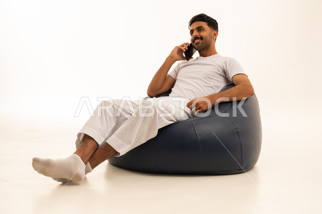 رجل سعودي بالملابس الداخلية التقليدية يستخدم الهاتف