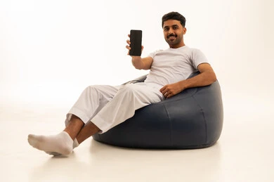 رجل سعودي يحمل هاتفا ذكيا على مقعد محشو