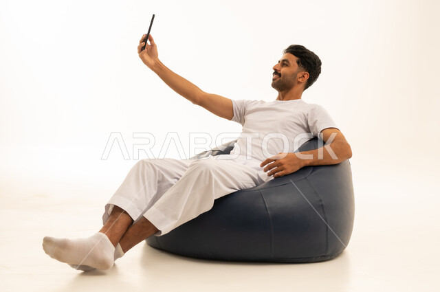رجل سعودي يستخدم الهاتف الذكي على كرسي بين باج