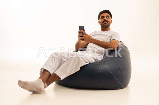 رجل سعودي يستخدم الهاتف الذكي على مقعد استرخاء