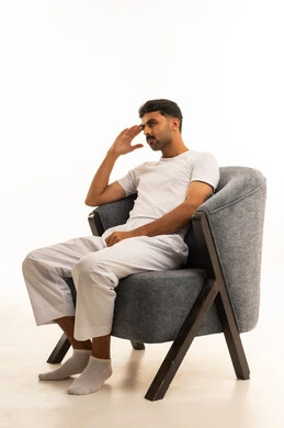 رجل سعودي بملابس بيضاء يجلس على كرسي رمادي