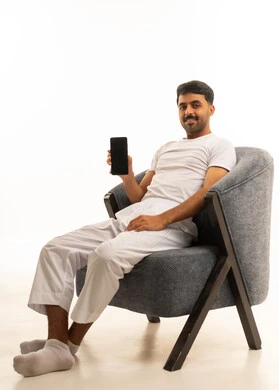 رجل سعودي يجلس على كرسي ويحمل هاتف ذكي