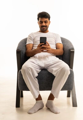 رجل سعودي بملابس داخلية بيضاء يستخدم الهاتف على كرسي