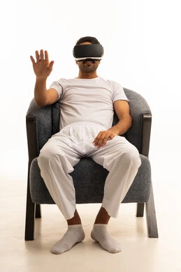 Saudi Man Using VR Headset Sitting in Grey Armchair