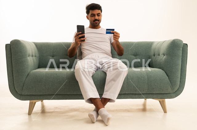 رجل عربي يستخدم بطاقة الائتمان على الأريكة