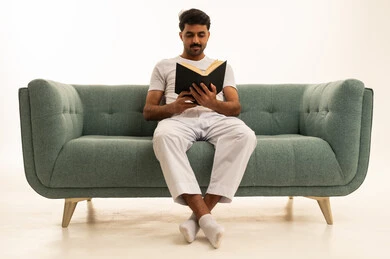 رجل سعودي يقرأ كتاباً على أريكة خضراء
