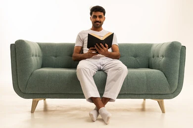 رجل سعودي يقرأ كتاباً أسود على أريكة في الاستوديو