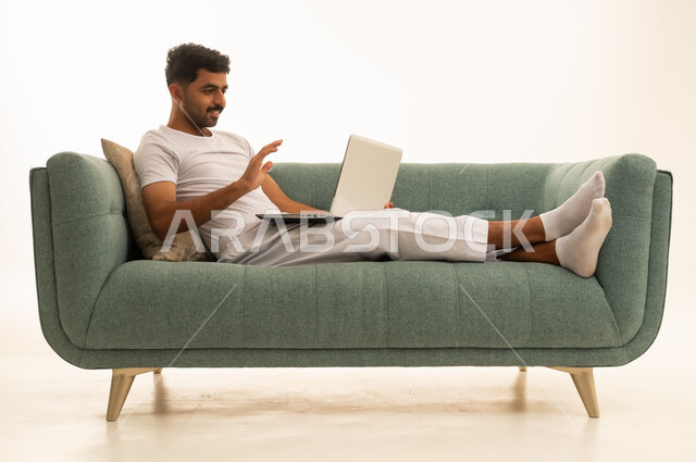 رجل سعودي يستخدم المحمول على أريكة خضراء