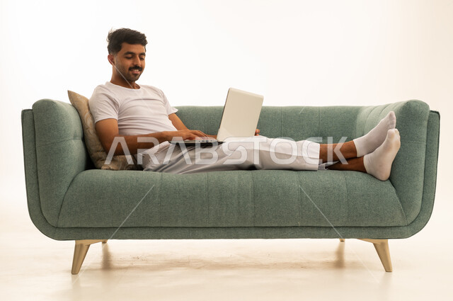 رجل سعودي يستخدم المحمول على أريكة خضراء