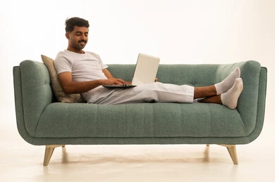 رجل سعودي يستخدم المحمول على أريكة خضراء