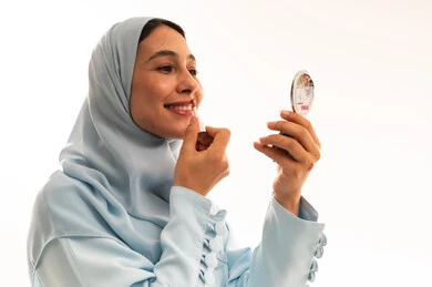 Saudi Woman Applying Lipstick in Studio Setting Saudi Woman Applying Lipstick in Studio Setting
