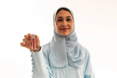 امرأة عربية بالحجاب تحمل منتج تجميل في الاستوديو
