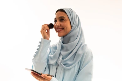 Arab Woman in Blue Hijab Applying Makeup with Sponge Arab Woman in Blue Hijab Applying Makeup with Sponge