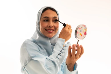 امرأة عربية تضع الماسكارا أمام المرآة في الاستوديو