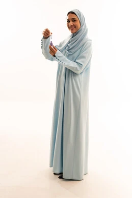 Arab Woman in Blue Abaya Holding Skincare Serum Arab Woman in Blue Abaya Holding Skincare Serum