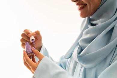 Saudi Woman in Blue Hijab Applying Purple Nail Polish