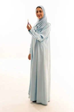 Arab Woman in Blue Abaya Holding Nail Polish Bottle