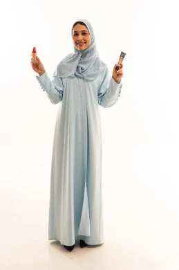 امرأة إماراتية بعباءة زرقاء تحمل منتجات تجميل