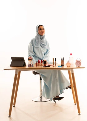 امرأة سعودية بالعباءة مع مستحضرات تجميل على المكتب امرأة سعودية بالعباءة مع مستحضرات تجميل على المكتب