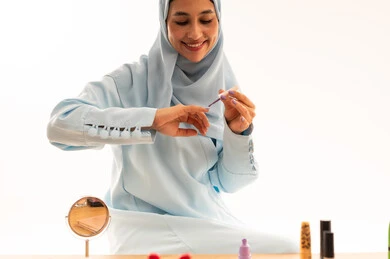 Muslim Woman Applying Nail Polish in Modest Blue Dress