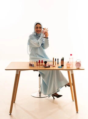 Arab Woman in Hijab Applying Makeup at White Studio Desk