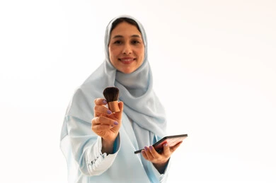 خبيرة تجميل سعودية تحمل فرشاة وباليت مكياج