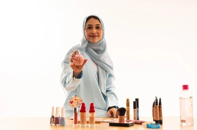 امرأة سعودية مع عطر ومستحضرات تجميل بخلفية بيضاء امرأة سعودية مع عطر ومستحضرات تجميل بخلفية بيضاء