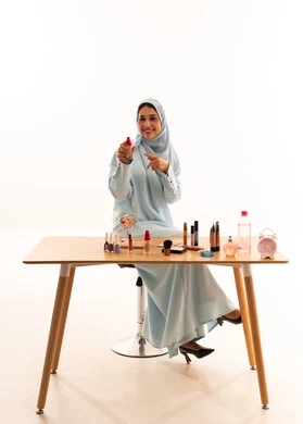 امرأة إماراتية بعباية زرقاء تراجع منتجات التجميل