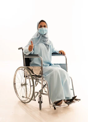 امرأة سعودية على كرسي متحرك ترتدي كمامة طبية
