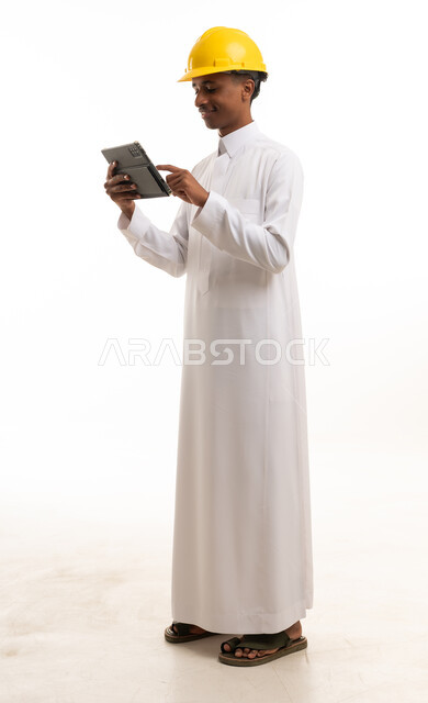مهندس سعودي بالثوب والخوذة يستخدم جهاز لوحي