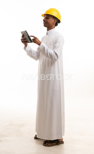 مهندس سعودي بالثوب والخوذة يستخدم جهاز لوحي