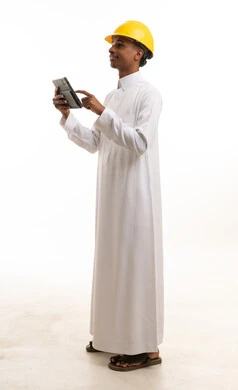 مهندس سعودي بالثوب والخوذة يستخدم جهاز لوحي