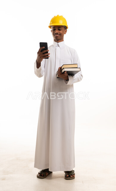 مهندس سعودي بالثوب الأبيض يحمل كتباً وهاتف