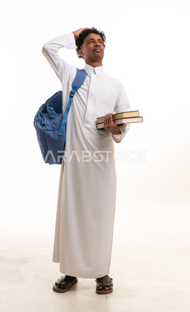 طالب سعودي بالثوب التقليدي يحمل كتب دراسية