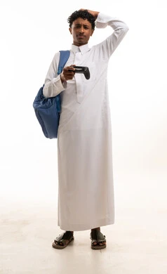 شاب سعودي بالثوب يحمل جهاز تحكم بالألعاب