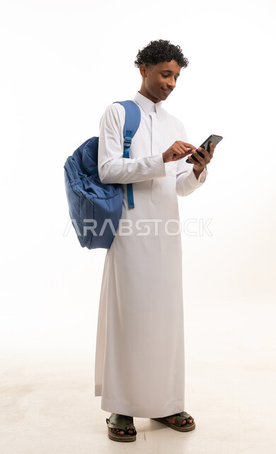 طالب سعودي بالثوب التقليدي يستخدم الهاتف الذكي