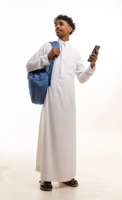 رجل سعودي بالثوب الأبيض يحمل هاتف وحقيبة ظهر
