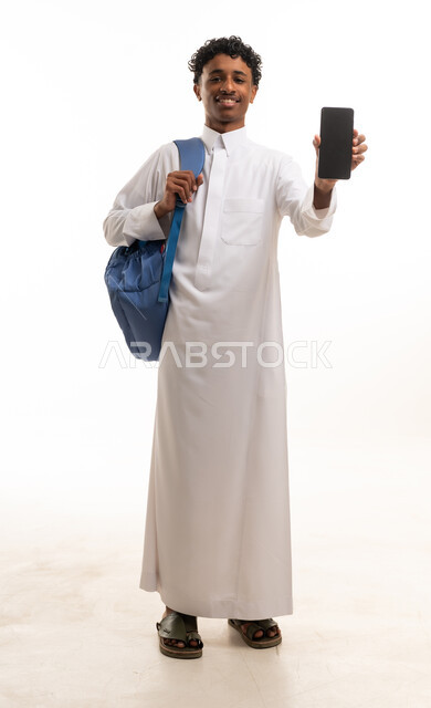 طالب سعودي بالثوب يحمل هاتفاً ذكياً مع حقيبة ظهر