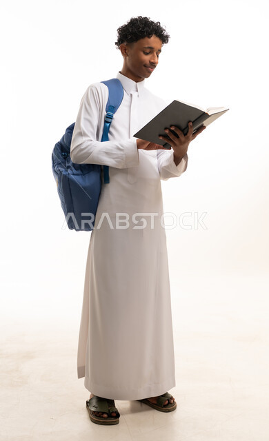 طالب سعودي بالثوب التقليدي يقرأ كتاباً